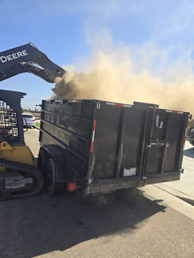 A dump truck is dumping dirt into a truck bed