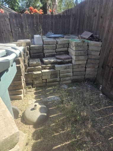 A pile of bricks sitting next to a wooden fence