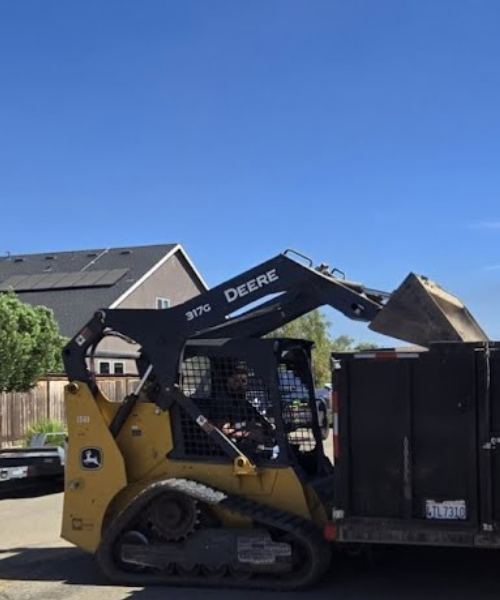 A man driving a skid steer in a driveway