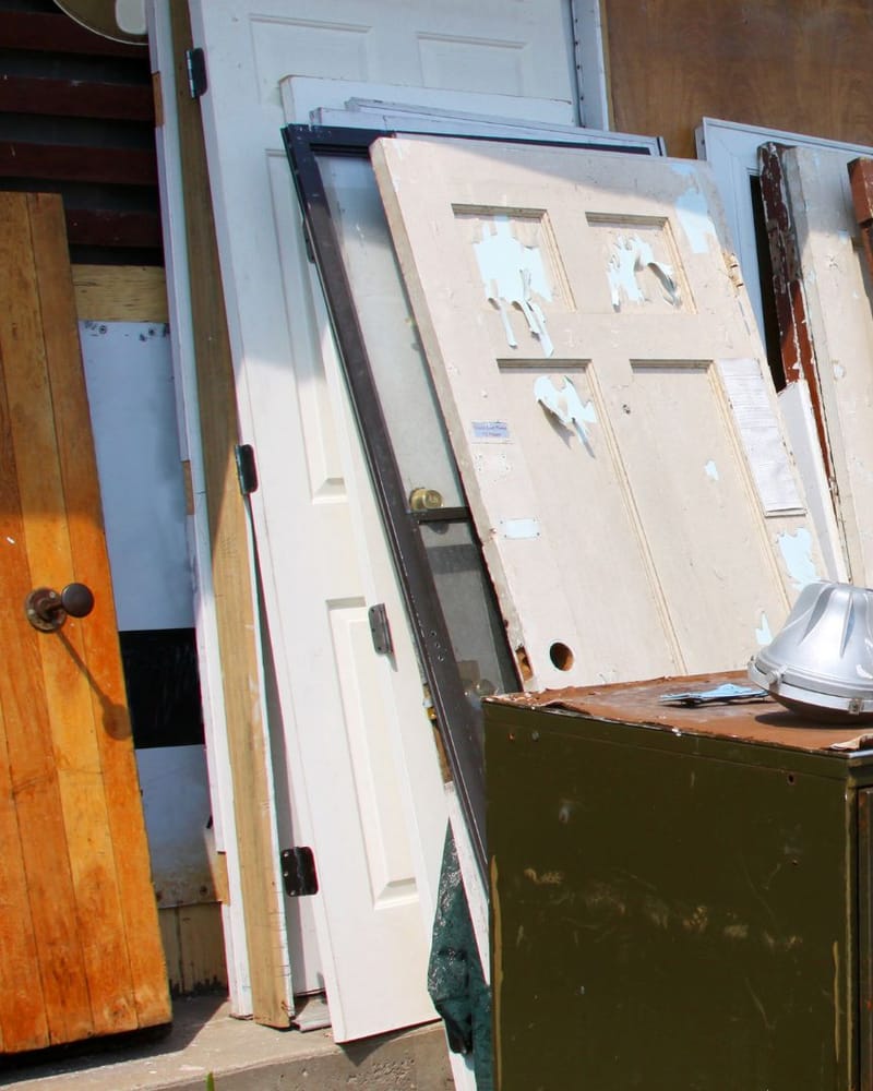 Removed timber, doors and structural material stacked after a backyard demolition in Fresno