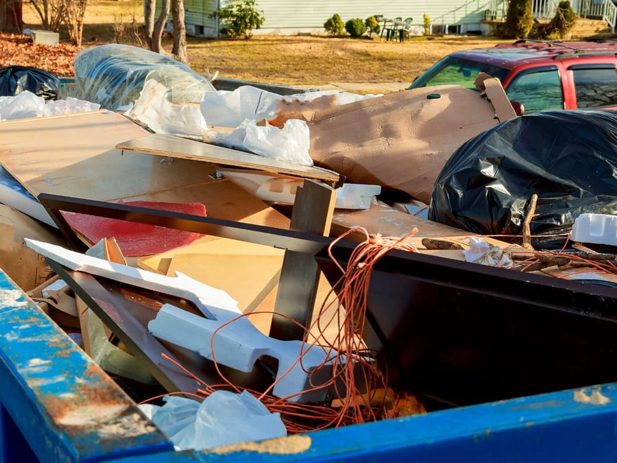 Dumpster loaded with mixed timber, wiring and restricted waste awaiting sorting