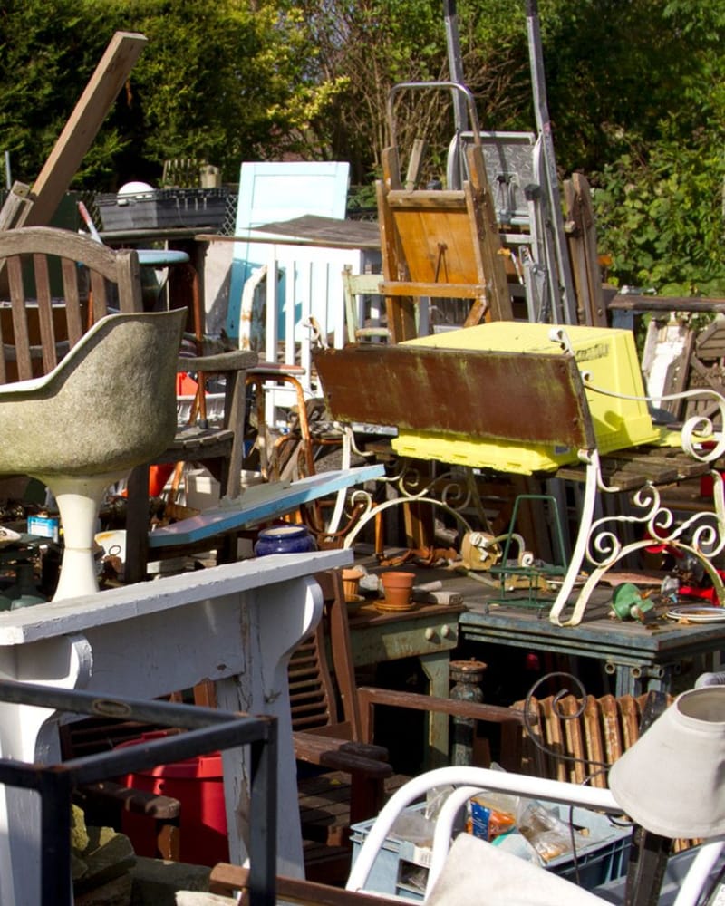 Old chairs, tables and dressers set out in a Fresno yard for furniture removal