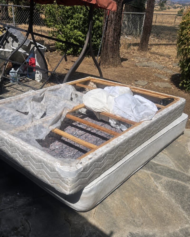 Old mattress and box spring set out on a Fresno driveway awaiting collection