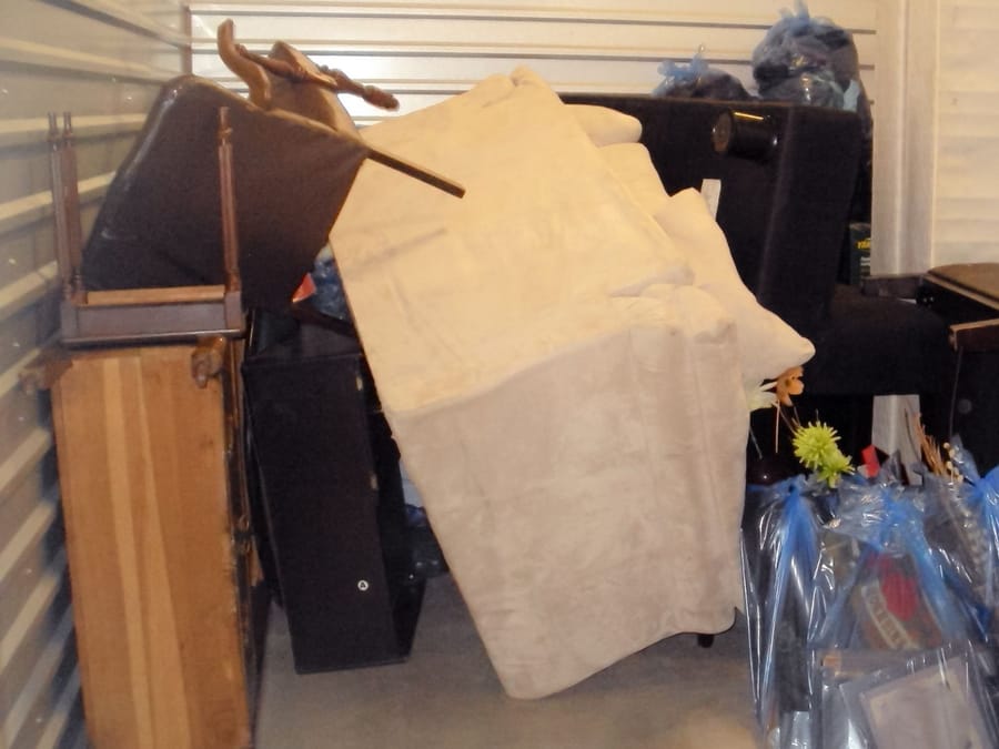 Crew carrying a heavy couch out through a Fresno living room during a furniture pickup