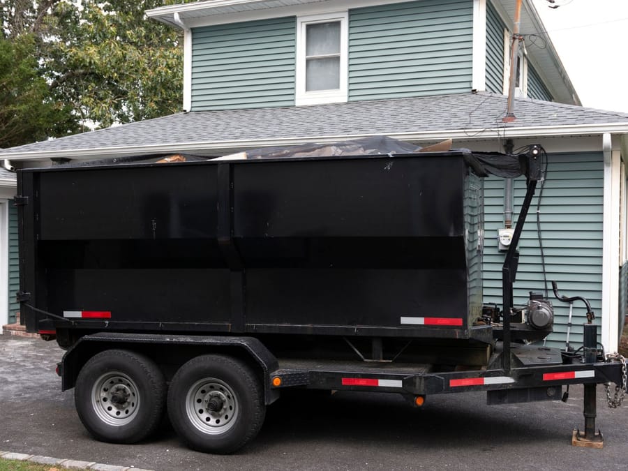 Dump trailer positioned beside a Fresno home for a same-day junk removal pickup