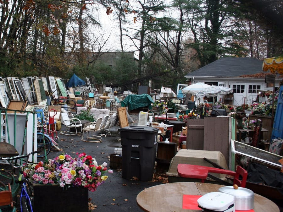 Back yard crowded with accumulated furniture, bins and stored items awaiting removal